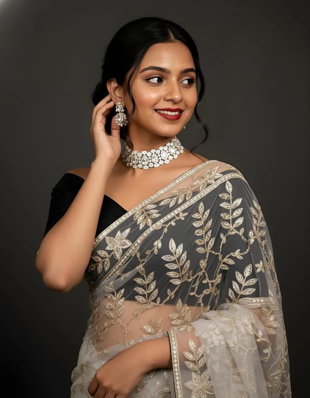 A stylish woman in a black and gold embroidered saree poses with sparkling floral jewelry for a modern Indian fashion portrait.